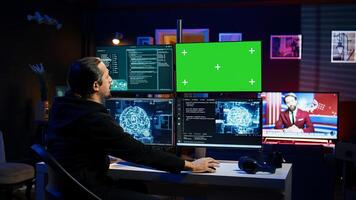 Hacker using green screen monitor and artificial intelligence to write spyware software gathering data from users. Scammer in apartment using AI and mockup PC display to do fraud using AI, camera B photo