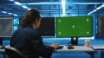 Engineer in server hub using green screen PC to repair equipment storing datasets. Professional using mockup computer to do debugging on rigs doing computational operations photo