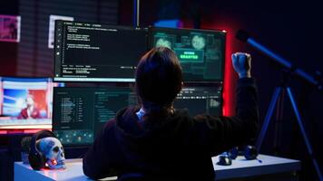 Happy hacker in secret hideout celebrating after managing to hide online activity after stealing data. Cheerful scammer feeling proud after successfully attacking victims using malware, camera B photo