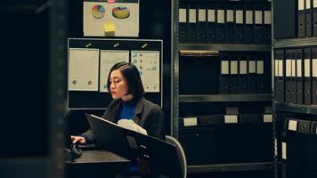 Legal advisor working on criminal private investigation in archive, studying old classified folders regarding interpretation of laws. Detective analyzing files to decipher coded messages. Camera A. photo