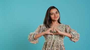 Portrait of jolly friendly indian woman doing heart symbol shape gesture with hands. Cheerful nurturing person showing love gesturing, isolated over studio background, camera A photo