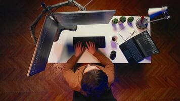 Top down view of remote worker typing code in personal office, using javascript language to develop software application. It specialist using multimonitor desktop setup to finish project, aerial shot photo
