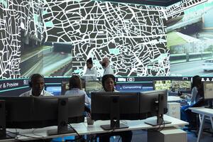 African american call center employee communicates satellite map routes to help couriers deliver orders in time. Operator works on express shipping service, CCTV surveillance navigation. photo