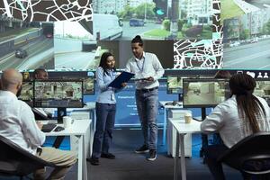Indian team of operators instructing their colleagues to use CCTV surveillance footage and guide couriers in traffic. Employees operating with global positioning system in satellite map. photo