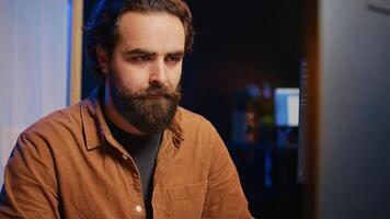 Software technician in apartment office deeply immersed in coding on computer at desk, close up. IT freelancer absorbed by work, focused on screen, writing lines of code at workstation, camera B photo