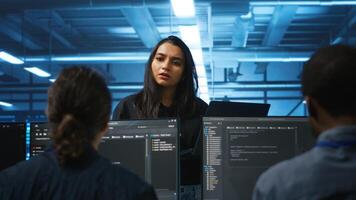 Supervisor in server hub managing multiracial team of programmers looking for equipment misconfigurations. Manager coordinating tech specialists fixing data center damages photo