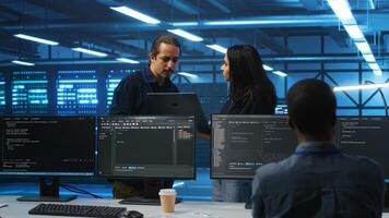 Multiethnic team of admins working in high tech server room capable of storing vast amounts of data. Diverse colleagues doing brainstorming, discussing ways to fix servers photo