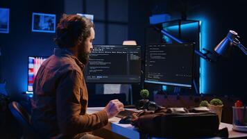 Freelancing software programmer arriving in personal office at home, resuming work on coding. Self employed IT specialist starting job shift in apartment, writing lines of code on computer, camera B photo