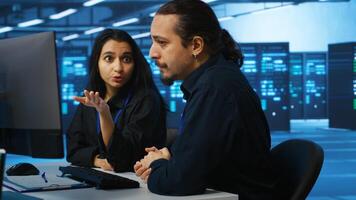 IT technicians in server farm brainstorming ways to repair equipment storing datasets. Colleagues at work in data center discussing how to mend rigs doing computational operations photo