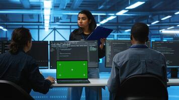 Isolated screen laptop in front of IT support workers coding on computers and talking with managers, upgrading equipment. Engineers at PC desk overseeing server clusters using chroma key notebook photo