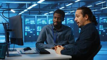 Multiracial engineers programming in high tech facility with server rows providing computing resources for different workloads. Diverse coworkers supervising data center supercomputers photo