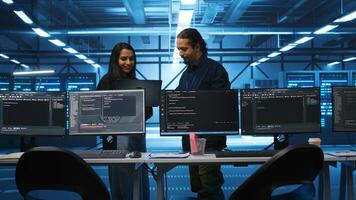 Multiracial colleagues in server hub workspace collaborating to fix servers providing computing resources for workloads. Engineers doing brainstorming while supervising data center supercomputers photo