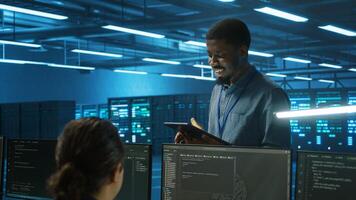 IT expert in server hub ensuring valuable data remains shielded from potential threats using tablet. Employee safeguarding data center against unauthorized access and vulnerabilities photo