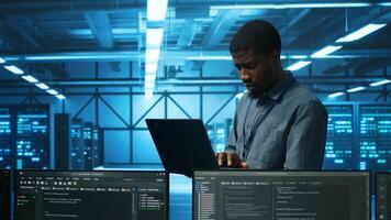Manager in server hub using laptop to find firewall misconfigurations affecting rackmounts performance. Supervisor checking systems bottlenecks leading to sluggish data transfer rates photo