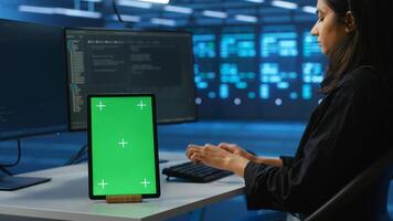 Focus on isolated screen tablet next to admin programming in server room providing computing resources for workloads. Chroma key device on desk used by worker supervising data center supercomputers photo