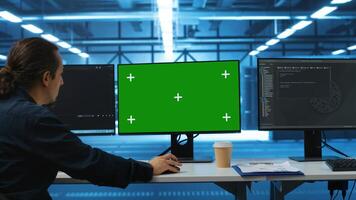 Software developer using green screen PC to do programming in server room providing computing resources for workloads. IT expert supervising data center supercomputers using mockup computer monitor photo