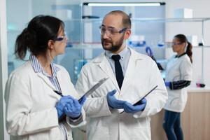 Hospital researcher team discussing virus prevention during microbiological investigation working in biochemistry hospital laboratory. Scientists developing healthcare treatment. Sickness examination photo