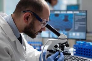 Closeup of specialist virus researcher analyzing coronavirus result using clinical microscope developing medical vaccine during biomedical investigation in scientific laboratory. Disease examination photo