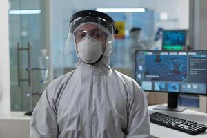 Portrait of biologist researcher in coronavirus protective medical equipment working at healthcare vaccine in biochemical hospital laboratory during biochemistry experiment. Virus investigation photo