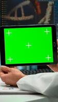 Back view of chemist man holding tablet with green mockup in modern equipped lab. Team of microbiologists doing vaccine research writing on device with chroma key, isolated display. photo
