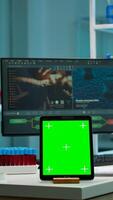 Team of scientists working in background of modern laboratory using tablet with green screen, mockup display, isolated chroma key monitor, analysing experiment evolution, high tech development lab. photo