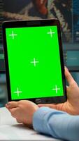 Close up of scientist woman holding tablet with green mockup in modern equipped lab. Team of microbiologists doing vaccine research writing on device with chroma key, isolated display. photo