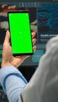 Back view of microbiologist doctor woman looking at mobile phone with green mockup in modern equipped lab. Team of scientist doing vaccine research writing on device with chroma key, isolated display photo