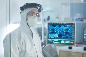 Portrait of biologist researcher developing medical vaccine against coronavirus working in microbiological laboratory using biotechnology. Scicentist man wearing protective equipment photo