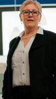 Portrait of successful senior entrepreneur standing in front of meeting desk looking at camera. Manager working in professional startup financial business modern company workplace ready for conference photo