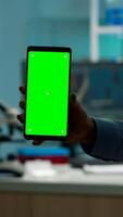 Close up of chemist's hand holding smartphone with green screen standing in biological laboratory while nurse bringing blood samples. Scientist using smartphone with mockup, chroma key display photo