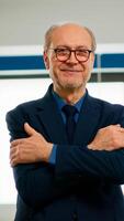 Elderly successful businessman entrepreneur standing looking at camera crossing arms and smiling. Manager working in professional start up financial business, modern company workplace ready for meeting photo