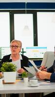Focused woman manager executive and multiethnic team analyzing paperwork discussing project plan sharing ideas brainstorm, work together at conference table office group corporate meeting photo