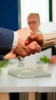 Close up of multiracial business partners standing in front of conference desk shaking hands after signing partnership contract. Diverse team being happy for successful negotiations in startup company photo