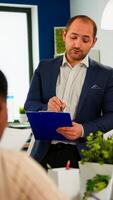Business leader presenting company strategy to diverse team using digital interactive whiteboard brainstorming analysing financial graphs, Multiethnical businesspeople working in professional start up photo