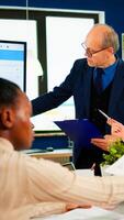 Mature man entrepreneur planning new project, briefing colleagues, explaning company strategy during brainstorming. Diverse team working in professional startup financial office during conference photo