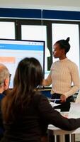 African project manager holding financial meeting showing statistical graphs and charts on interactive whiteboard touchscreen device. Executive director working in broadroom of creative agency. photo