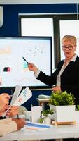 Chief analyst holding meeting presentation for a team of economists. Manager showing digital interactive whiteboard with growth analysis, charts, statistics, data, diverse people working in broadroom photo