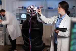 Specialist neurologist doctor monitoring brain evolution of patient with eeg headset on head during neuroscience experiment in modern laboratory. Physician researcher analyzing nervous system activity photo