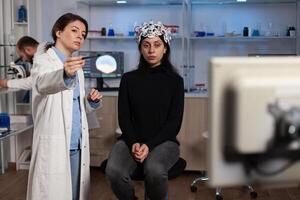 Physician neurologist doctor analyzing brain evolution of patient with eeg scanner on head during neuroscience experiment in modern laboratory. Physician researcher monitoring nervous system activity photo