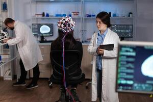 Specialist researcher doctor monitoring brain activity evolution during neuroscience experiment in high tech laboratory. Woman patient with eeg headset having neurology disease. Medicine service photo
