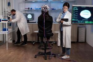 Neurologist engineer doctor monitoring brain activity evolution during neuroscience experiment in medical laboratory. Woman patient with eeg scanner having neurological disease. Medicine service photo