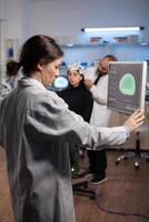 Neurologist specialist analyzing nervous system tomography on monitor while specialist doctor adjusting eeg scanner of woman patient during medical experiment. Neurology team monitoring brain activity photo