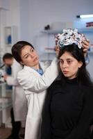 Researcher engineer woman putting eeg scanner on woman patient head during neurology experiment in medical laboratory. Neurologist doctor analyzing brain evolution monitoring nervous system activity photo