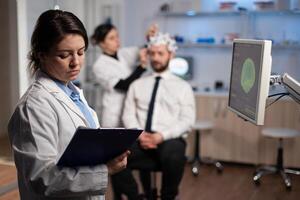 Medical neurologist woman adjusting eeg headset monitoring brain activity of man patient during medical experiment in modern laboratory. Scientist engineer analyzing nervous system photo