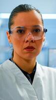 Tired chemist doctor looking at camera sighing in modern equipped lab. Multiethnic team examining virus evolution using high tech and chemistry tools for scientific research, vaccine development. photo