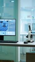 Modern empty biological applied science laboratory with technological microscopes, glass test tubes, micropipettes, desktop computers and displays. PC's are running sophisticated DNA calculations. photo
