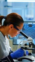 Scientist looking at biological samples under microscope typing on pc. Team of chemists working in lab, examining virus evolution using high tech for scientific research of vaccine development. photo
