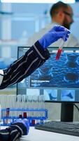 Scientist doctor looking at blood sample and typing on computer while coworker opening door using digital computer with touch scan. Woman examining virus evolution using high tech and chemistry tools photo