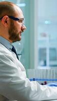 Scientist in lab coat analysing blood sample from test tube. Viorolog researcher in professional laboratory working to discover medical treatment, team of doctors analysing vaccine evolution photo
