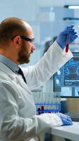 Scientist man examining blood samples and liquid working in modern equipped laboratory. Team of doctors analysing vaccine evolution using high tech researching diagnosis against covid19 photo